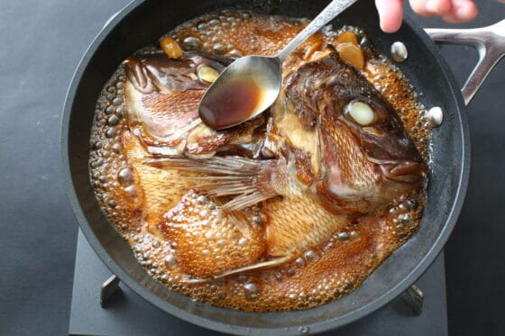煮汁をかけながら鯛の頭を煮る