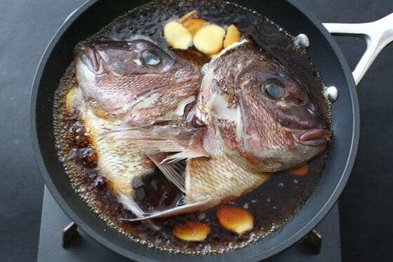 鯛の頭をフライパンに並べて調味料を加えて煮る