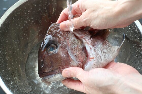 鯛の頭にふった塩を洗い流す