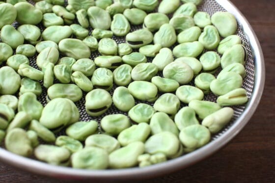 茹でた空豆をザルに広げる