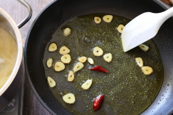 ニンニクと唐辛子にパスタ（スパゲティ）の茹で汁を加えて乳化させる