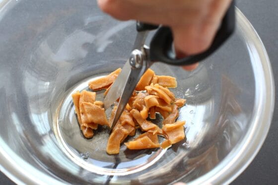 味付けメンマをキッチンバサミで切り分ける