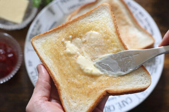 焼き上がった食パンにバターを塗る