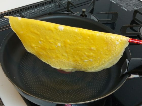 菜箸で薄焼き卵を持ち上げる