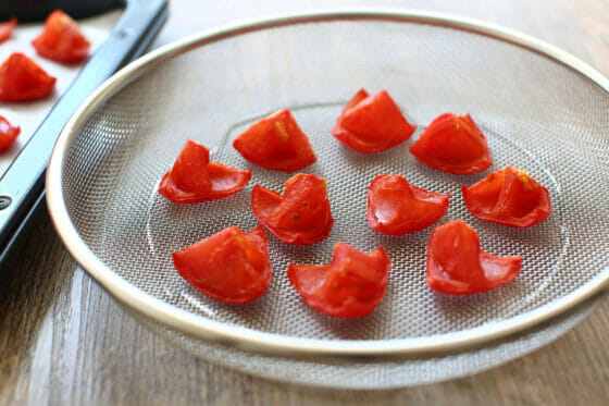 オーブンで焼いた大玉トマトをザルに乗せて太陽の光を当てる