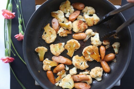 カリフラワーとウインナーに醤油を加えて炒める