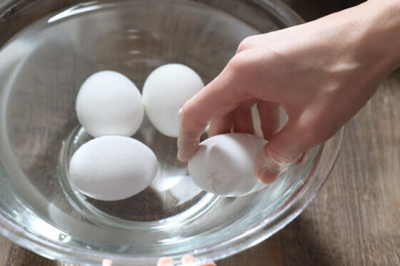 フライパンで蒸したゆで卵を水で冷やして殻にヒビを入れる