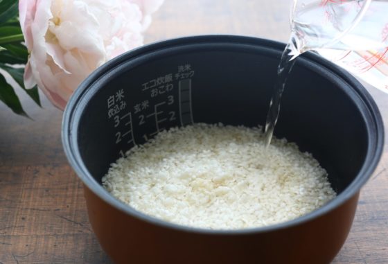 米を入れた炊飯器に水を注ぐ