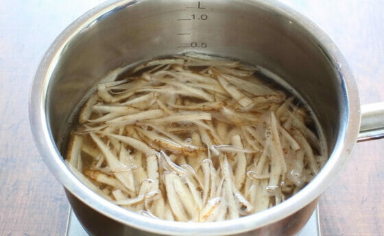 水とだしの素とごぼうを鍋に入れる
