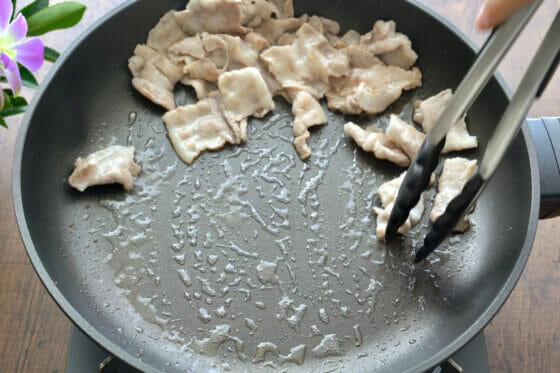 炒めた豚バラ肉をフライパンの端に寄せる