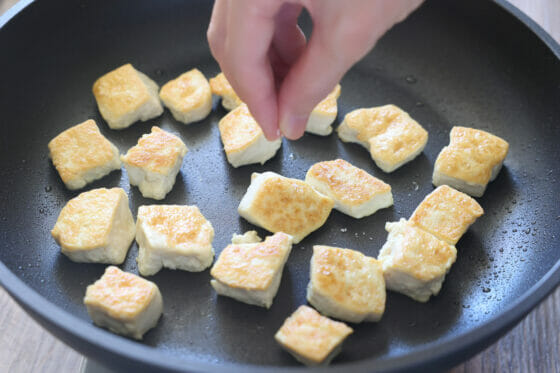 炒めた豆腐に塩をする