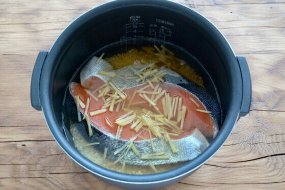 米の入った炊飯器に塩鮭を入れる