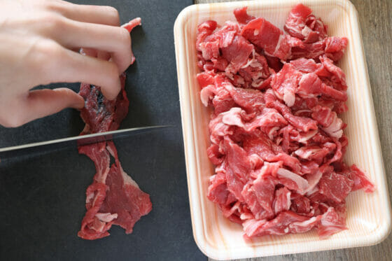 大きめの牛肉を包丁で切る