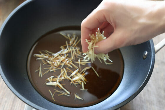 調味料が入った鍋に生姜の千切りを入れる