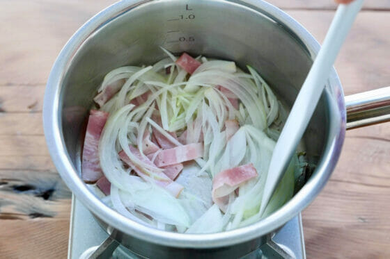 鍋にオリーブオイルを引いてベーコンと玉ねぎを炒める