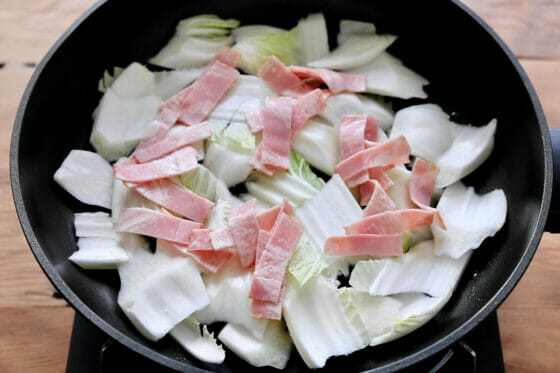 フライパンにオリーブオイルを引いて白菜の芯を広げてベーコンを乗せる