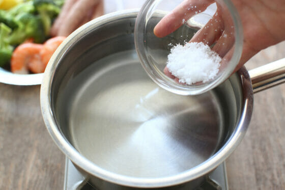 鍋で沸かした湯に塩を加える