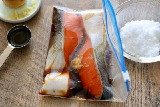 袋に入れた鮭に調味料を加える