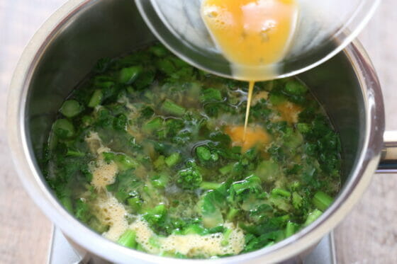 菜の花の味噌汁に卵を回し入れる