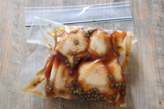 茹でた鶏肉と山椒の実の醤油漬けを保存袋で密閉する