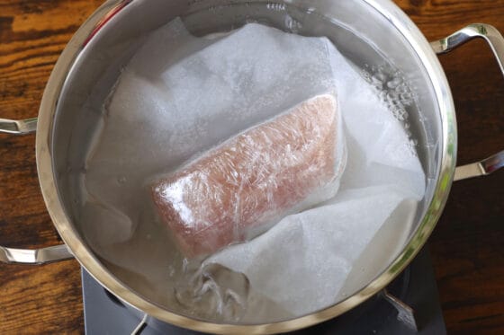 キッチンペーパーで底面と側面を覆った胸肉を沸騰した湯に入れる