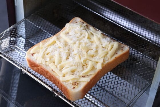 チーズをのせた食パンをトースターに入れる