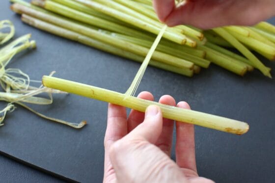 野ぶきの茎の表面の筋を手で引っ張って取り除く