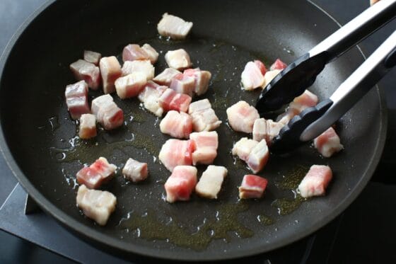 サイコロ状に切った塩漬け肉をフライパンで炒める