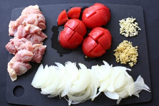 玉ねぎ・にんにく・しょうが・トマト・鶏もも肉を切る