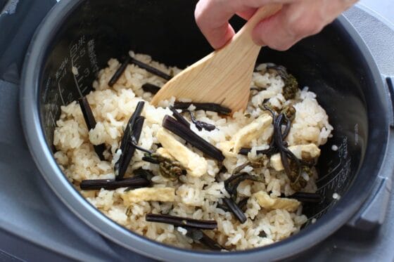 わらびの炊き込みご飯をしゃもじで混ぜる