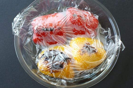 焼き上がったパプリカにラップを密着させて蒸らす