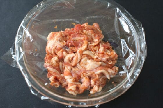 肉に調味料を加えてラップをかぶせて味をなじませる