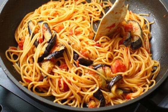 フライパンにパスタを入れて、なすとトマトとパスタソースと絡める
