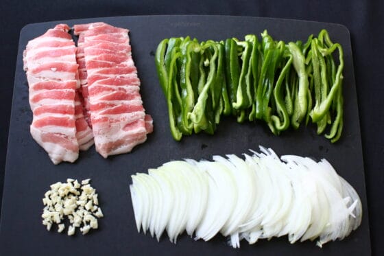 ピーマンと玉ねぎとニンニクと豚バラ肉を切る