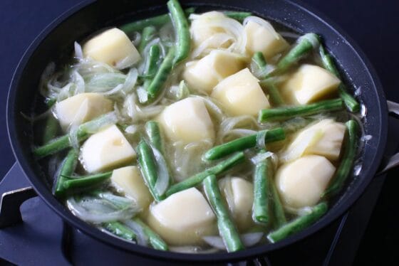 炒めた野菜に水とコンソメを加える