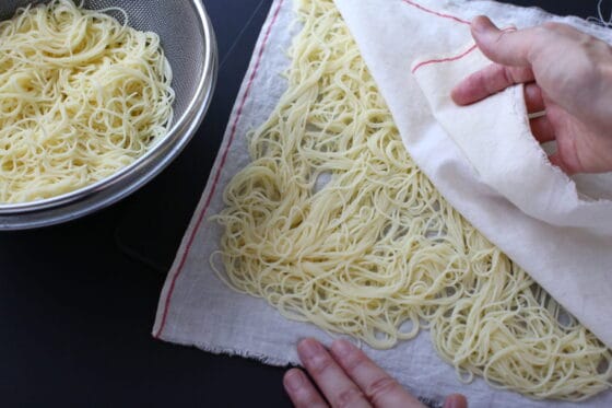 茹でたパスタの水気を布巾で拭き取る