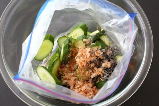 ポリ袋に入った調味液に、きゅうり・塩昆布・かつおぶし・白ごまを加える