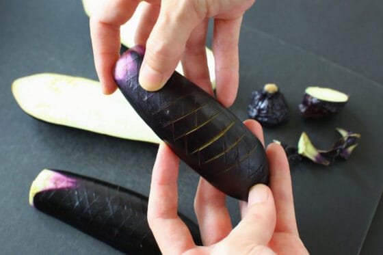 ヘタを切り落とし縦半分にしたなすの皮目に格子状の切り込みを入れる