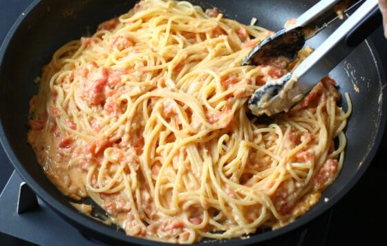 茹でたパスタをソースに加えて和える