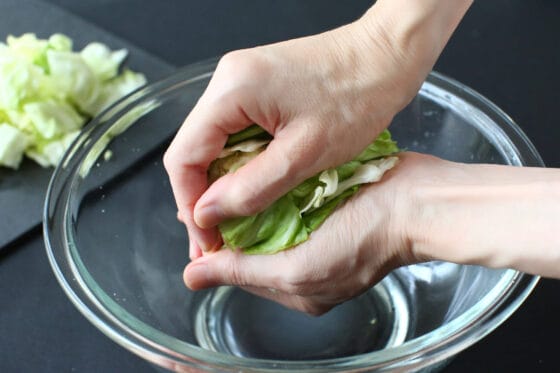 塩もみしたキャベツの水気を手で絞る