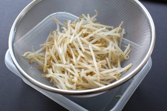 電子レンジで加熱したもやしをザルに上げて水気を切る