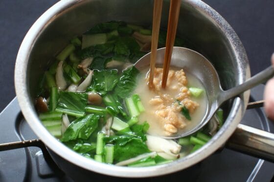 白味噌をお玉と菜箸で溶き入れる