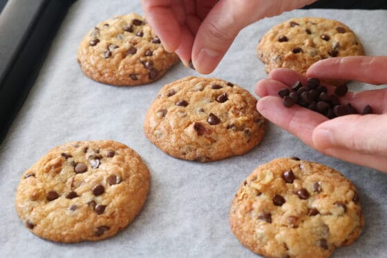 焼き立てのクッキーに追加のチョコチップを押し込んで仕上げる