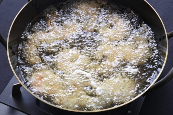 温めた揚げ油に衣をつけたエビを入れる