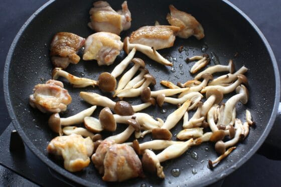 焼き色が付いた鶏肉にしめじを加えて炒める