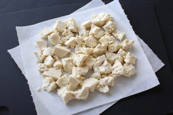 豆腐を小さめに手でちぎってキッチンペーパーの上に乗せる