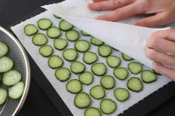 塩もみ後のきゅうりをキッチンペーパーで優しく押さえて水気を取る