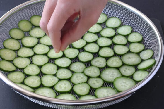 きゅうりの輪切りを盆ザルに並べ、塩を全体に振りかけておく