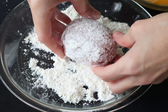 成形したスコッチエッグに小麦粉をまぶす