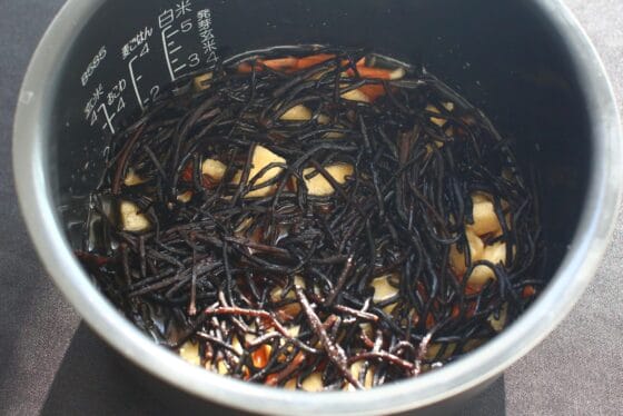 米や調味料の上にひじきなどの具材を広げる